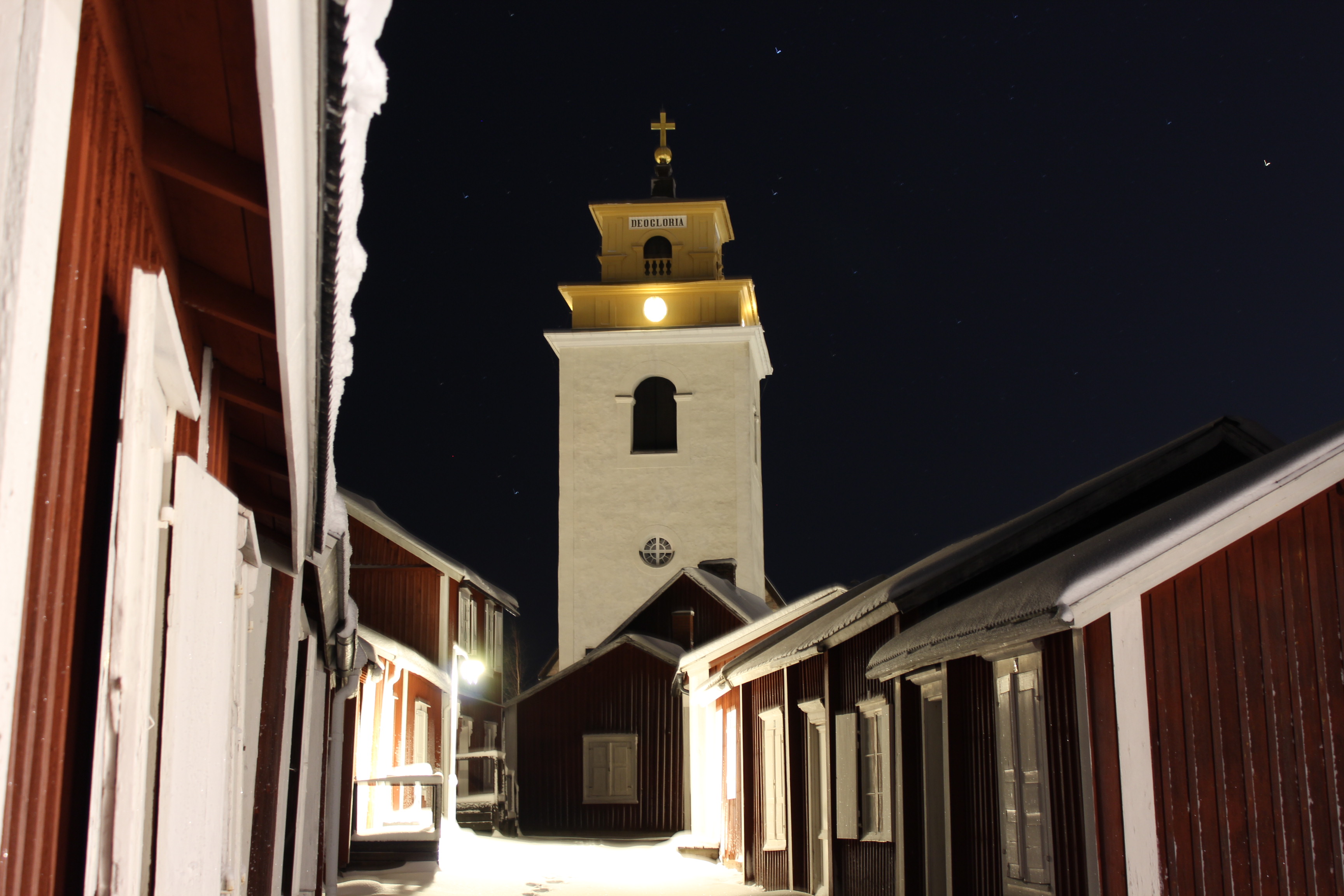 Kyrktornet och några röda kyrkstugor på kvällen